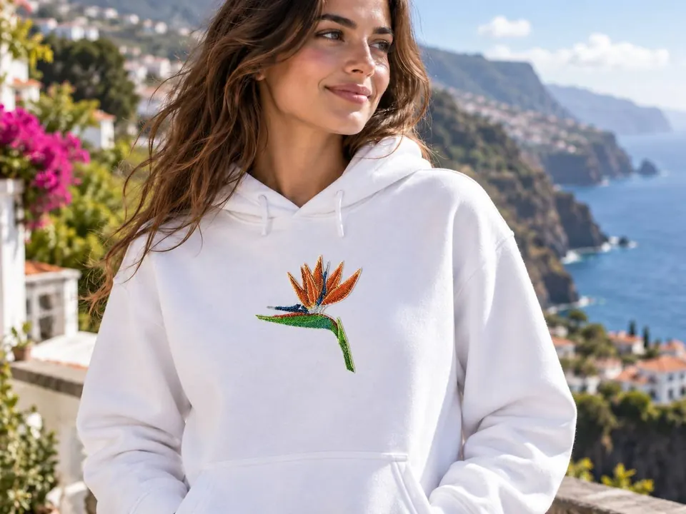 Weißer Hoodie mit gestickter Strelitzie, dahinter die Küste Madeiras